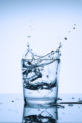 Splash in a glass with ice. Splashes of clean water in a glass with ice, on a white background.
