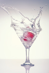 Frozen splashes of clean, spring water, in a glass with frozen strawberries. White background.