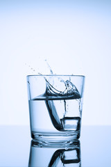 Frozen splashes of clean, spring water, in a glass with ice, on a white background.