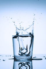 Splash in a glass. Frozen splashes of clean, spring water, in a glass with ice, on a white background.