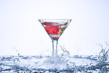 Frozen explosion of freshness from water, in a cocktail glass with strawberries, on a white background.