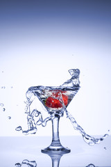 Frozen explosion of freshness from water, in a cocktail glass with strawberries, on a white background.