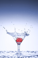 Frozen explosion of freshness from water, in a cocktail glass with strawberries, on a white background.