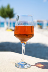 One glass of cold rose wine served on the beach with beautiful sea view. Relax concept. Bright sunny day with blue sky.