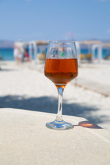 One glass of cold rose wine served on the beach with beautiful sea view. Relax concept. Bright sunny day with blue sky.