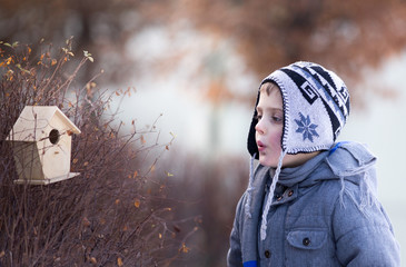 Boy whistling beside bird house