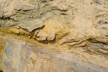Surface of the rock with a granite stone texture. Designer background for interiors. Stone surface of a yellow texture close-up.