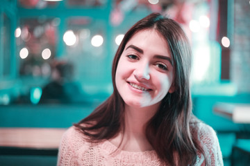 happy young woman sitting in the restaurant and smiling on camera, close up