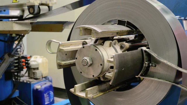 Cold rolled steel coil on decoiler of machine in metalwork manufacturing.