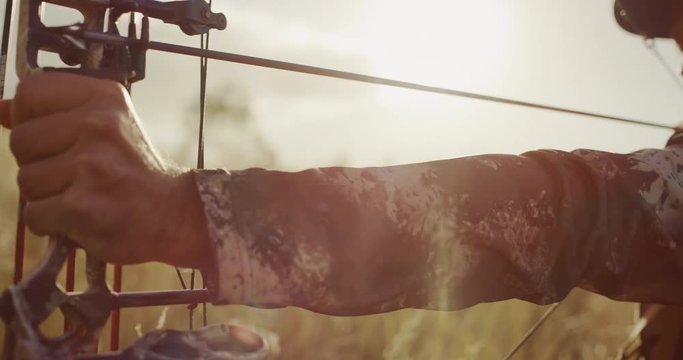 Close up of experienced bowhunter man drawing an arrow in the afternoon light