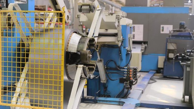 Cold rolled steel coil on decoiler of machine in metalwork manufacturing.