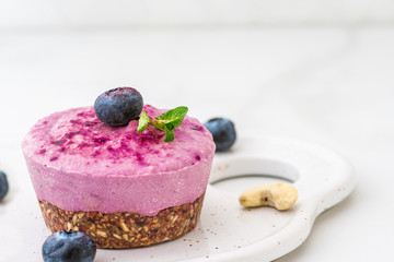 homemade raw blueberry and acai vegan cake with fresh berries, mint, nuts. healthy vegan food concept