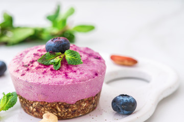 blueberry and acai vegan cashew cake with fresh berries, mint, nuts. healthy vegan food concept