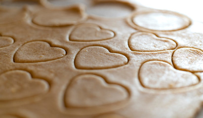 close up of biscuit dough with cutted out cookies in heart shape for valentines day