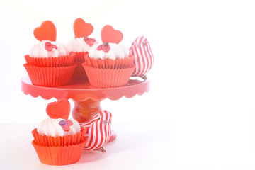 Red and white Valentine's cupcakes with hearts and love bug decorations with lens flare.