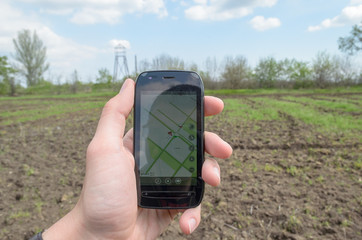A hand is holding a phone in his hand. GPS navigation is enabled on the phone. Thus, the...