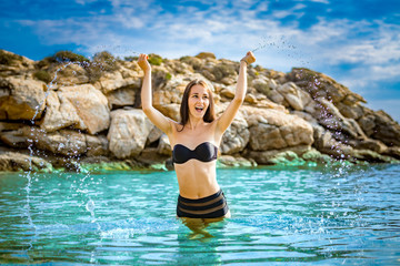 Cheerful pretty woman splashing at the sea, playing and laughing