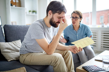 Desperate man holding letter with rejection of job application while his wife shouting at him