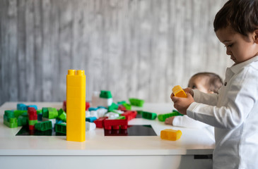Obraz premium Two happy baby playing with toy blocks.