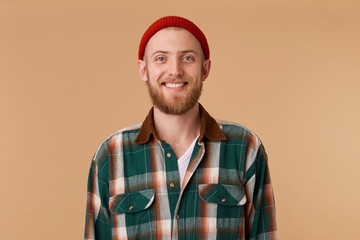 Attractive bearded man in red hat with broad smile showing healthy teeth. A close up portrait of...