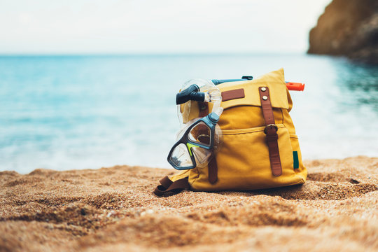 hiker tourist yellow backpack and swimming mask on background blue sea ocean horizon on sand beach, blurred panoramic seascape blank, traveler relax holiday concept, sunlight view in trip vacation - Powered by Adobe