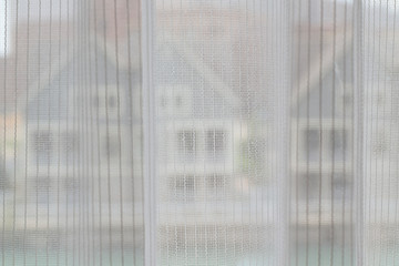 Fine lace curtain with faint outline of houses