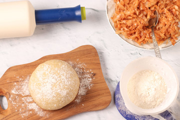 Ingredients for cooking dumplings: dough, fried cabbage and flour. View from above