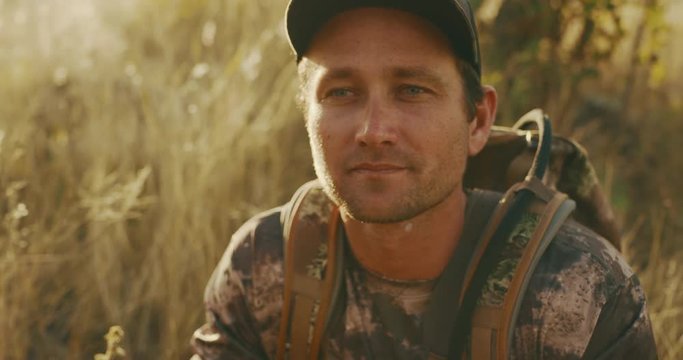 Orbit shot of calm bowhunter looking through his binoculars