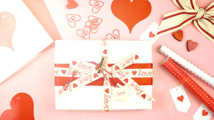 Happy Valentine's Day overhead flat lay wrapping gift and writing cards with lens flare.