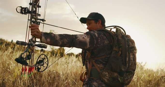 Orbit shot of experienced bowhunter drawing an arrow in his compound bow