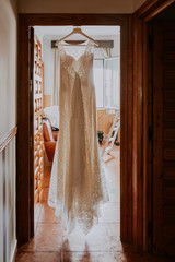 a white wedding dress hanging in a rustic house