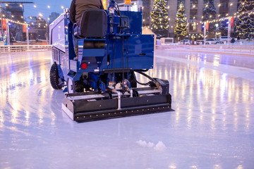 A machine for restoring or smoothing ice rides on an ice rink in the evening.