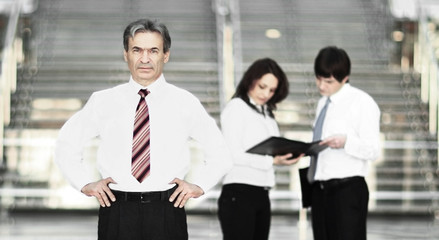 Portrait of a smiling handsome businessman. working team communicating at background
