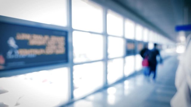 Defocused silhouette rear view of woman walking on the horizontal escalator in international airport - direction to terminal, flight change, luggage, lounge - slow motion cinematic colors