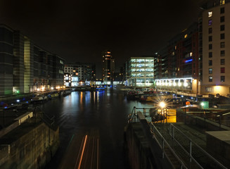 Fototapeta na wymiar cityscape view of clarence dock in leeds at night showing the lock gates and water surrounded by buildings