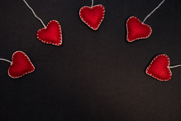 A row of red hearts from felt. Background for congratulations on Valentine's Day. Background for sale. Black lettering paper.