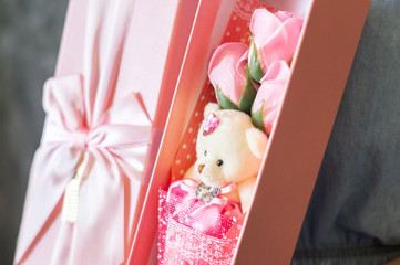 Florist's work: A girl demonstrates a box with a bouquet of pink roses and a teddy bear.