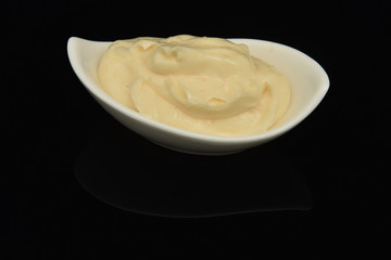 Mayonnaise in small bowl isolated on black  background