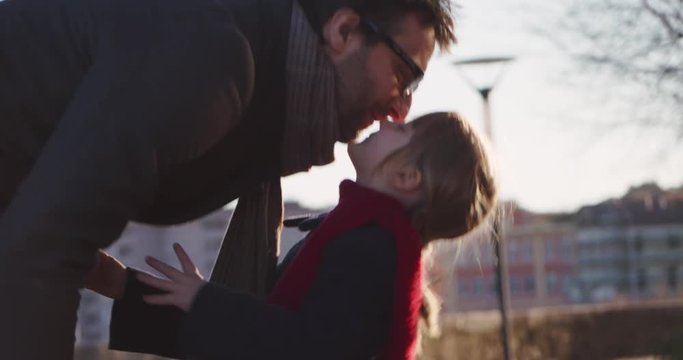 Daughter child kissing her dad. Modern future transport technology.Active Family.Park sidewalk urban outdoor.Warm sunset cold weather backlight.4k slow motion 60p video