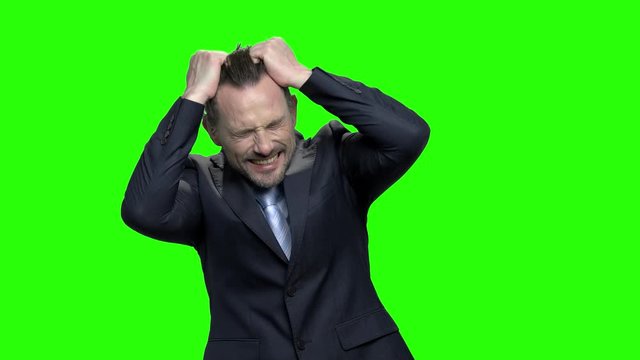 Frustrated mature businessman pulling his hair. Sad stressed man has nervous breakdown because of business bankruptcy or being fired. Green hromakey background for keying.