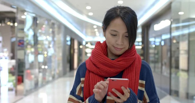 Woman search on the discount coupon on cellphone inside shopping mall