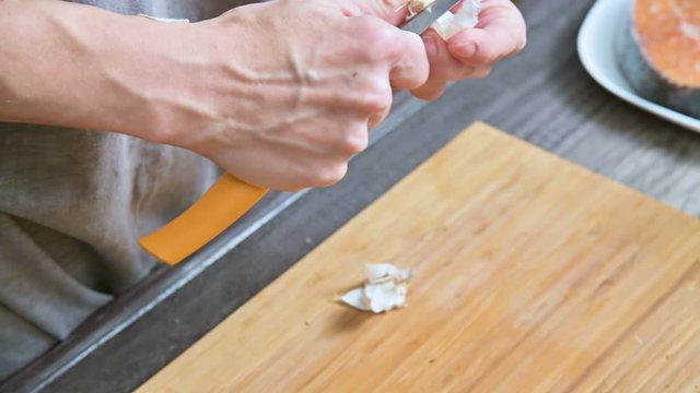 Close-up of female hands at home kitchen clean garlic from the peel. Shallow depth of field