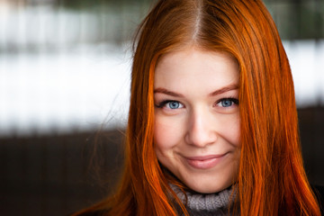 portrait of a young blue-eyed smiling girl with bright red hair