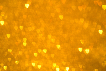 Bokeh golden blurred background of yellow heart shape lights.