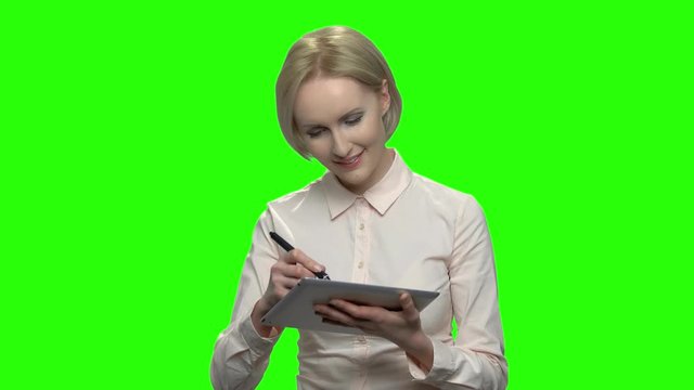 Beautiful businesswoman writing on table pc gadget. Green screen hromakey background for keying.