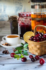Hot spicy lingonberry or cranberry tea in cup, rustic background