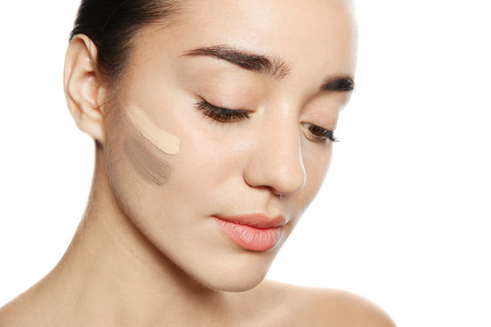 Young woman with different shades of skin foundation on her face against white background