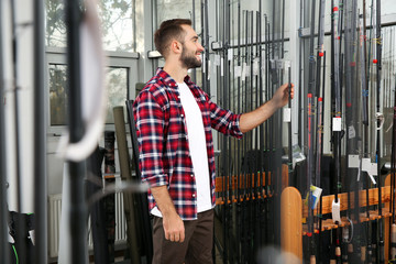 Man choosing fishing rod in sports shop