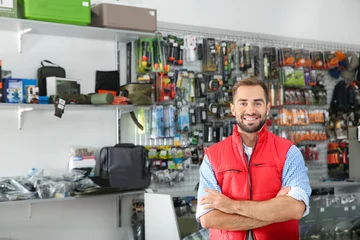 Door stickers Hunting Salesman standing near showcase with fishing equipment in sports shop. Space for text