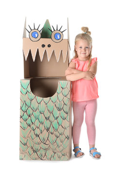 Cute little girl playing with cardboard dragon on white background